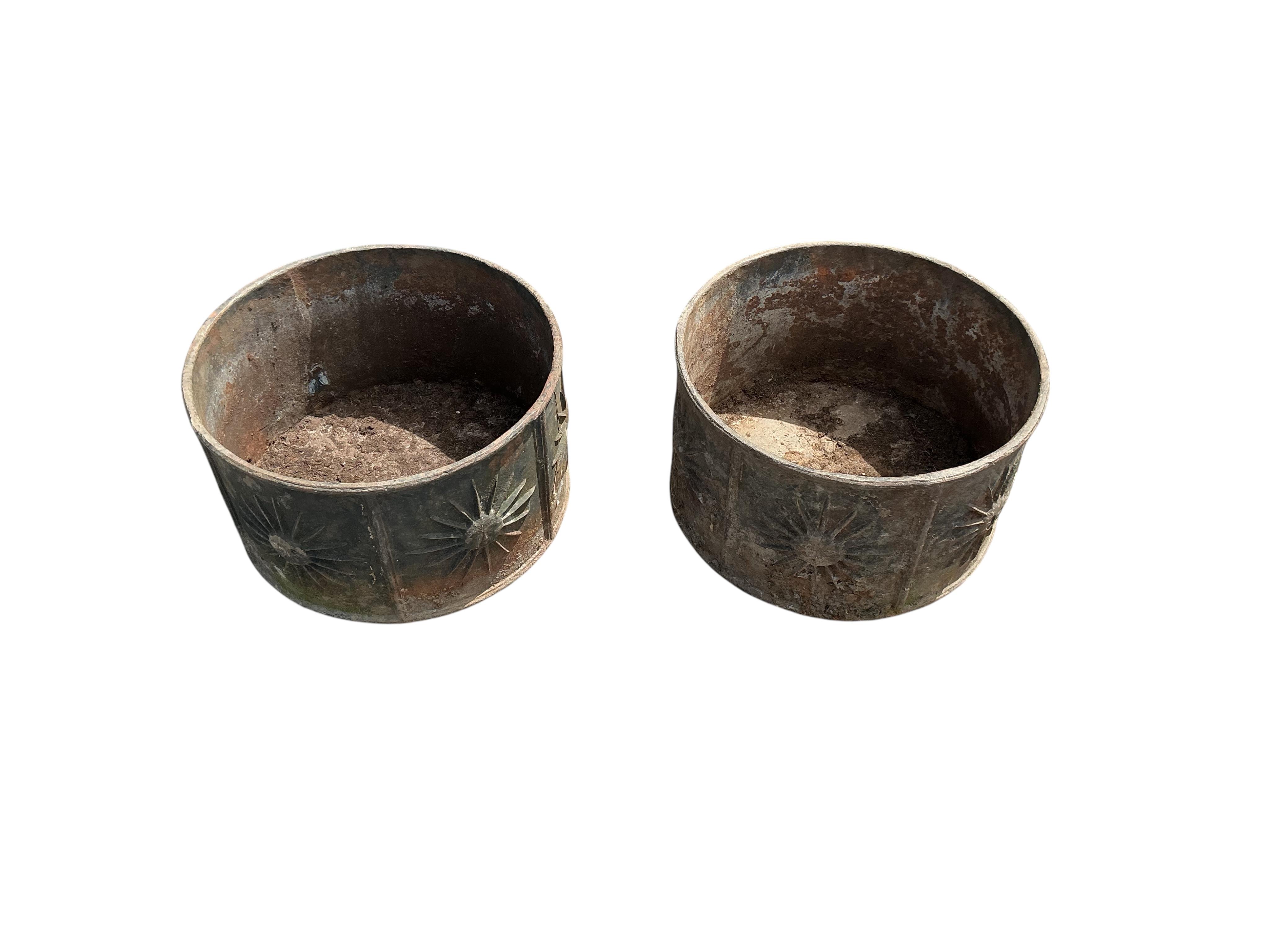 A pair of circular iron planters with cast relief sunburst panels, diameter 52cm, height 30cm